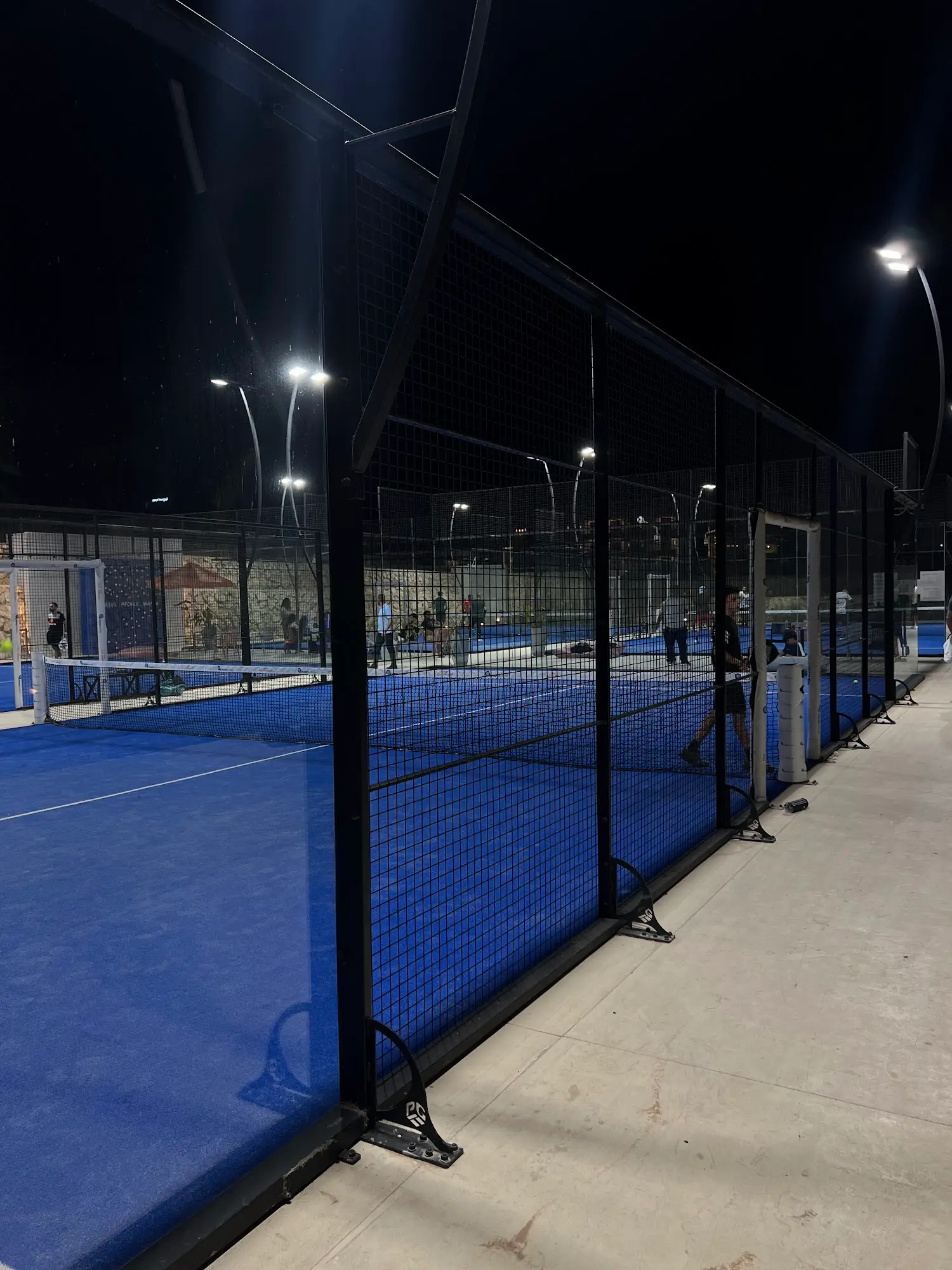 A row of floodlit blue padel courts at Padel Mania