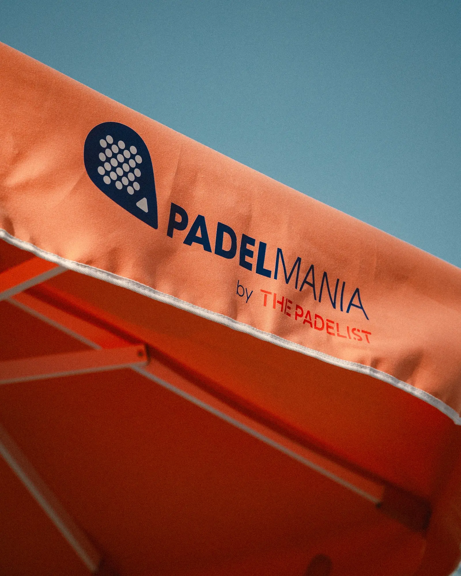 Padel Mania logo on the club's orange canopy against the sky