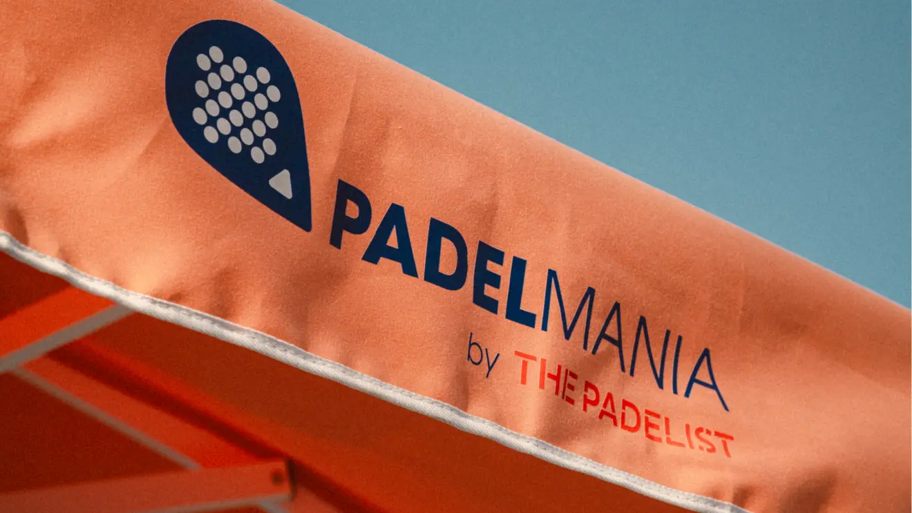 An orange Padel Mania canopy printed with the club logo